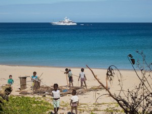 A huge yacht and train of smaller ships sailing by the beach of Nosy Mitsio.