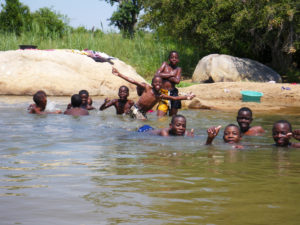 Kids swimming in the river to avoid the heat.