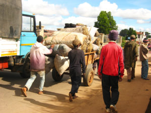 A few guys hauling a big load of charcoal along the road.