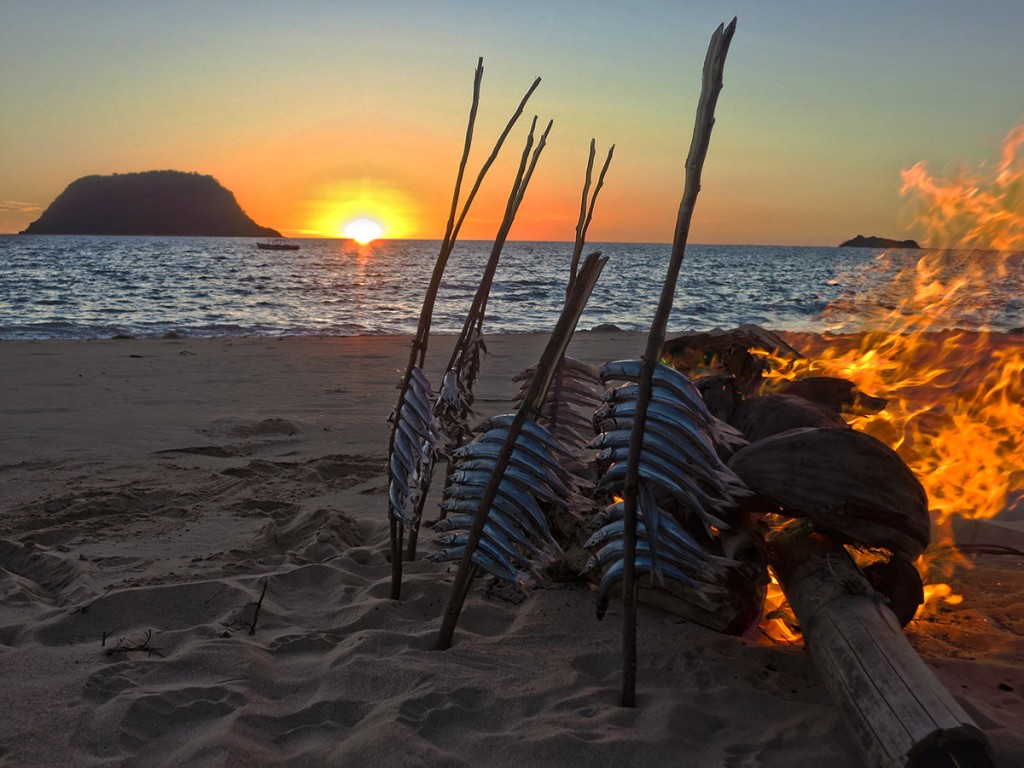 Smoking fish on our village's beach at sunset. These small fish were caught from the women's style of netfishing, called "magnaroba".